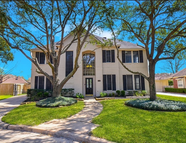 view of front of house featuring a front yard, fence, and brick siding