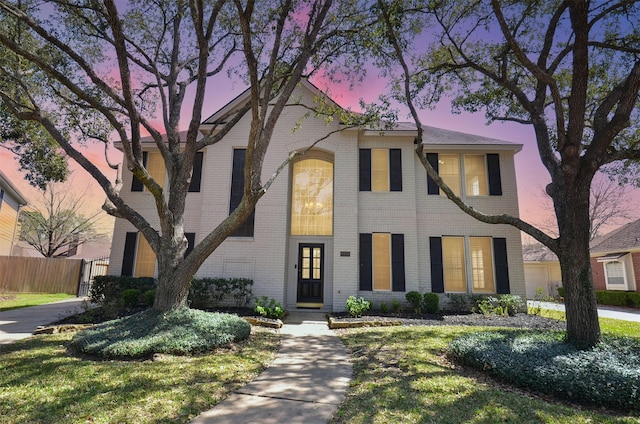 view of front of house featuring brick siding and fence