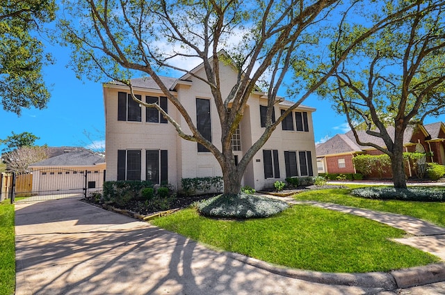 view of front of house with brick siding, concrete driveway, a front lawn, and a gate