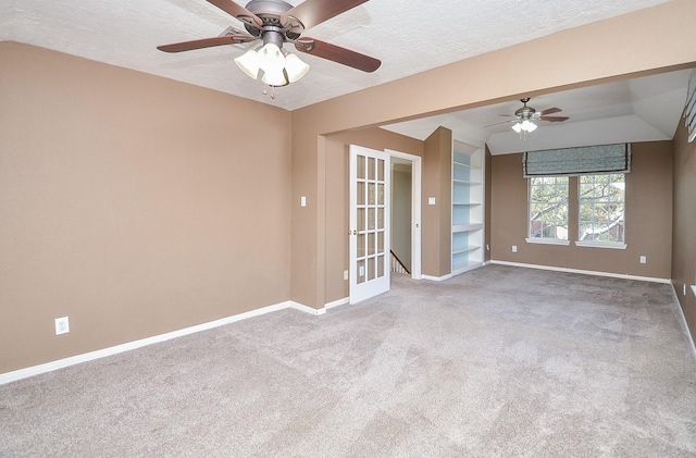 carpeted empty room featuring baseboards, ceiling fan, built in features, french doors, and a textured ceiling