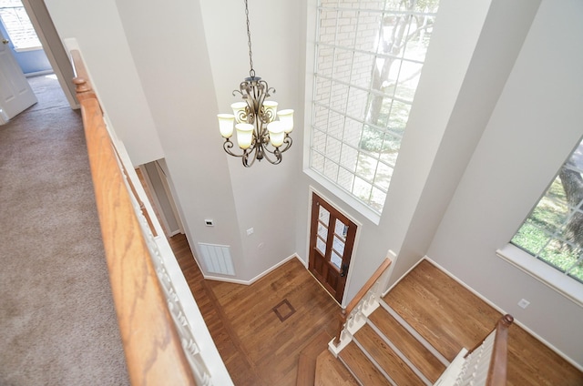 foyer entrance with a chandelier, a healthy amount of sunlight, a high ceiling, and wood finished floors