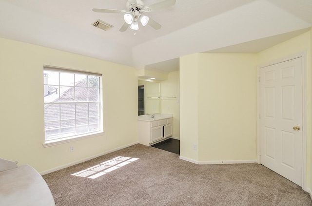 empty room with visible vents, a sink, dark carpet, baseboards, and ceiling fan