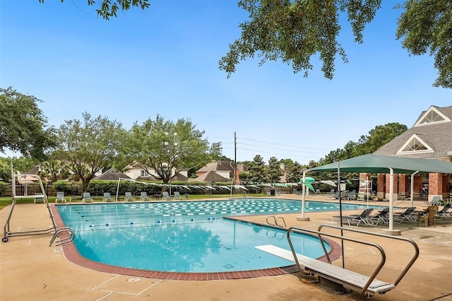 pool with a diving board, fence, and a patio area