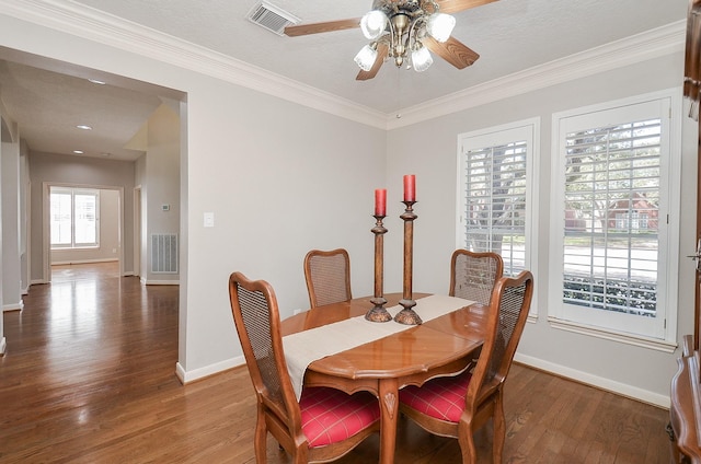 dining room with ornamental molding, wood finished floors, visible vents, and ceiling fan