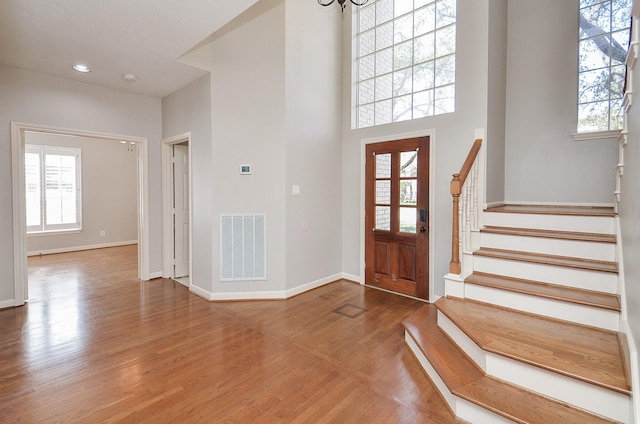 entrance foyer with stairs, wood finished floors, visible vents, and baseboards