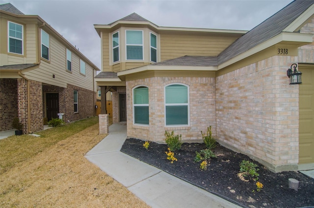 view of exterior entry with a yard and brick siding