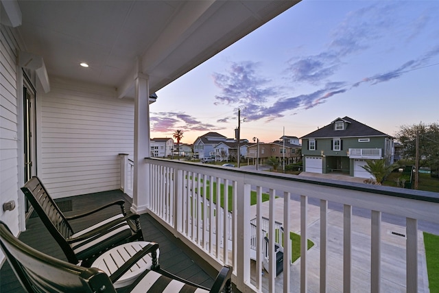 balcony at dusk featuring a porch and a residential view