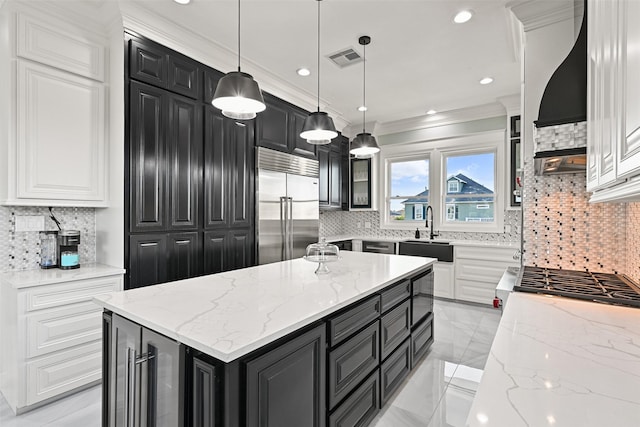 kitchen with visible vents, dark cabinetry, a sink, and built in fridge