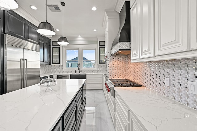 kitchen featuring built in fridge, dark cabinets, visible vents, custom range hood, and crown molding