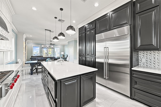 kitchen featuring visible vents, ornamental molding, open floor plan, built in appliances, and dark cabinets