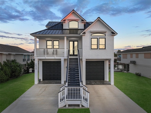 coastal home with covered porch, stairway, a standing seam roof, and a front lawn