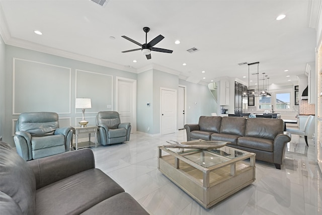 living room with ornamental molding, visible vents, a decorative wall, and a ceiling fan