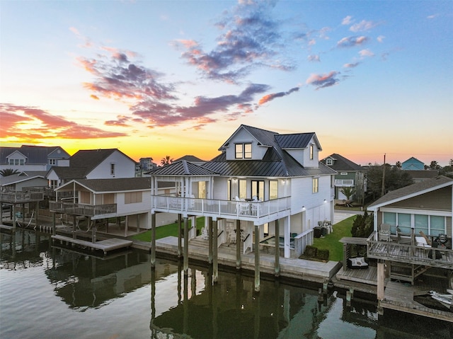 back of house featuring a standing seam roof, a water view, and metal roof