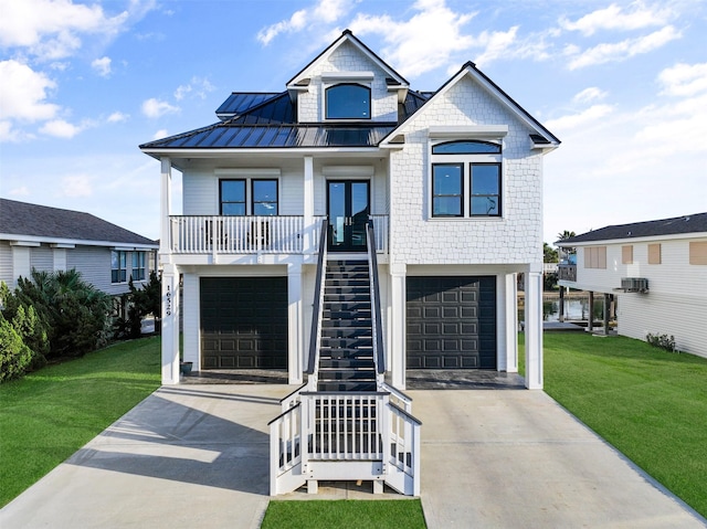 beach home featuring stairs, concrete driveway, a front lawn, and a standing seam roof