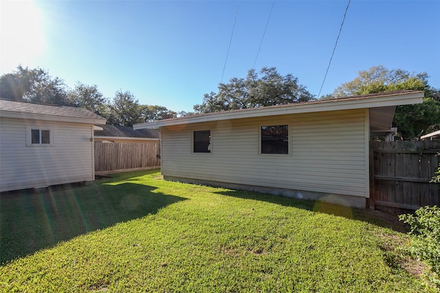 rear view of house featuring a yard, an outdoor structure, and fence