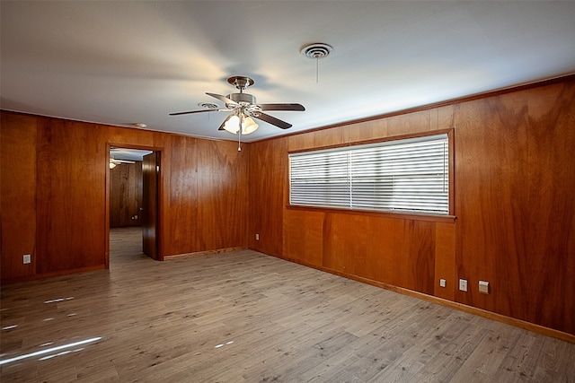 unfurnished room with ceiling fan, wood walls, and wood finished floors