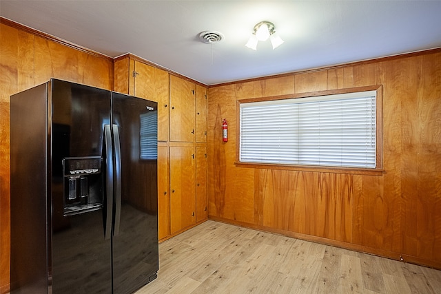 kitchen featuring wooden walls, black fridge with ice dispenser, visible vents, light wood-style floors, and brown cabinets