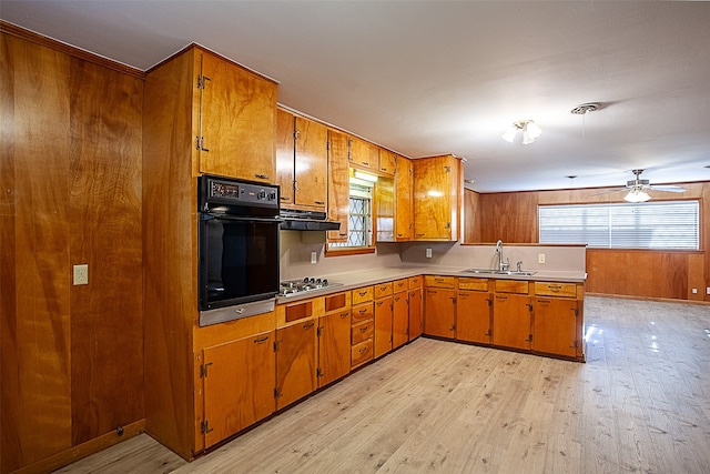 kitchen with black oven, brown cabinetry, a sink, and stainless steel gas stovetop