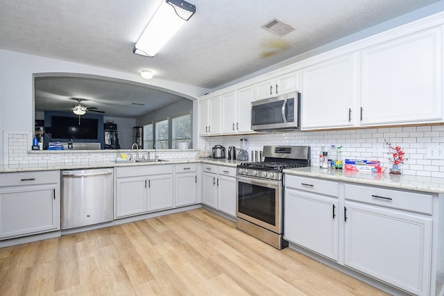 kitchen featuring light wood finished floors, stainless steel appliances, visible vents, a ceiling fan, and a sink