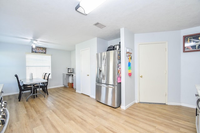 kitchen with light wood-style floors, visible vents, stainless steel refrigerator with ice dispenser, and baseboards