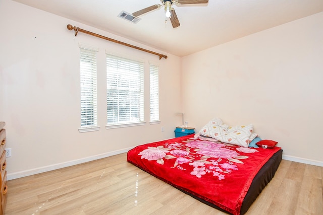 bedroom with a ceiling fan, baseboards, visible vents, and wood finished floors