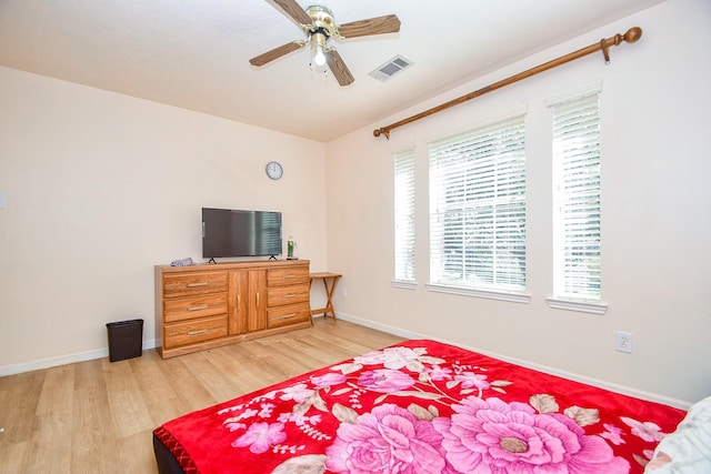 bedroom featuring baseboards, a ceiling fan, visible vents, and light wood-style floors