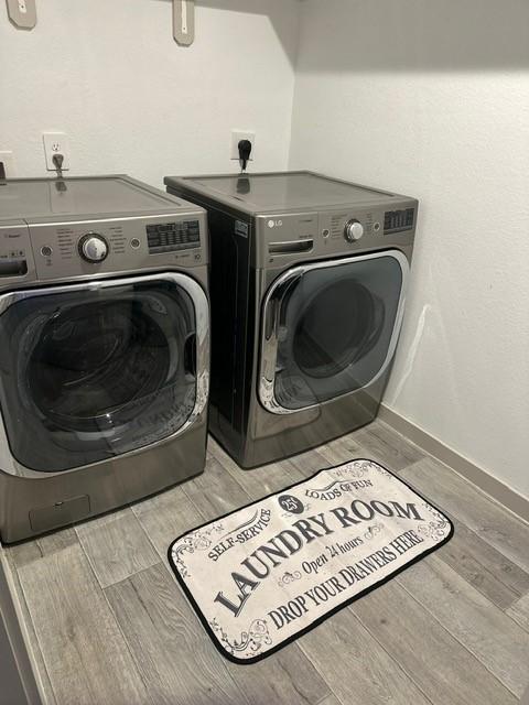 laundry room with laundry area, wood tiled floor, baseboards, and washer and dryer