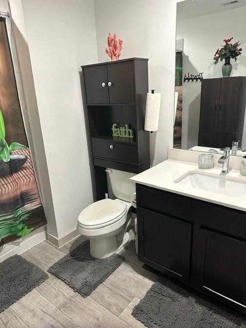 bathroom with visible vents, vanity, toilet, and wood finished floors