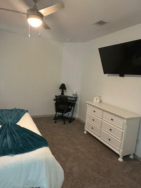 bedroom with dark carpet, visible vents, and a ceiling fan