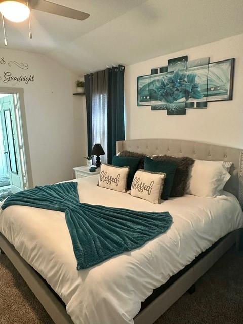 bedroom featuring a ceiling fan, vaulted ceiling, and carpet flooring