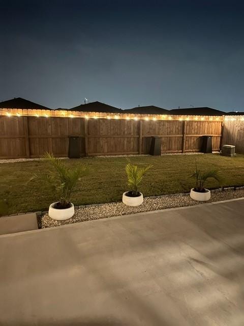 yard at night featuring a patio area and a fenced backyard