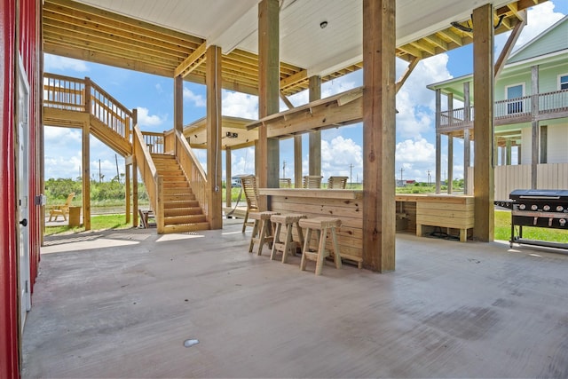 view of patio with outdoor dry bar, area for grilling, and stairs