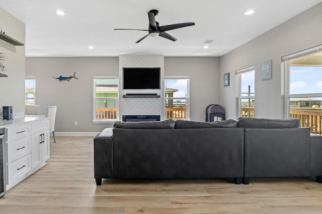 living area with light wood-type flooring, a large fireplace, visible vents, and recessed lighting