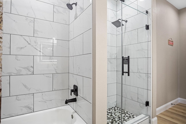 full bathroom with tiled shower / bath combo, baseboards, and wood finished floors