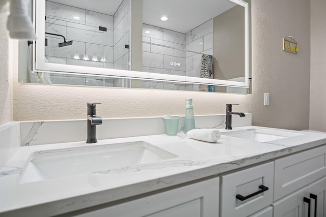 full bath with a textured wall, tiled shower, and a sink