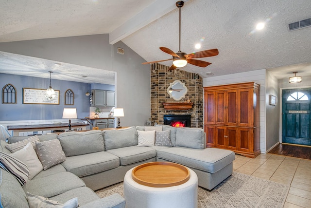 living room with visible vents, vaulted ceiling with beams, light tile patterned floors, a fireplace, and a textured ceiling