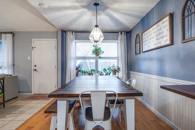 dining space featuring a wainscoted wall, a textured ceiling, and wood finished floors