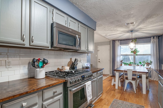 kitchen featuring visible vents, wooden counters, stainless steel appliances, decorative backsplash, and light wood-type flooring