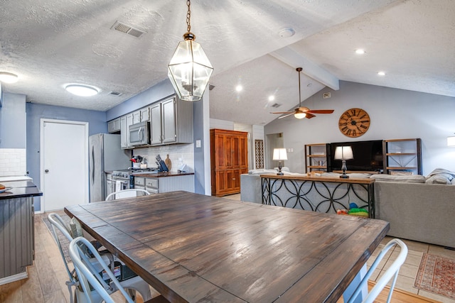 dining space with a ceiling fan, visible vents, lofted ceiling with beams, light wood-style flooring, and a textured ceiling