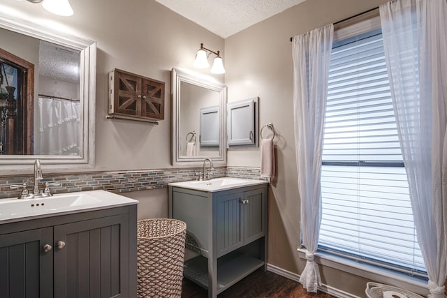 full bath featuring a textured ceiling, two vanities, and a sink