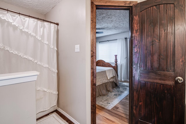 bathroom featuring connected bathroom, a textured ceiling, baseboards, and wood finished floors