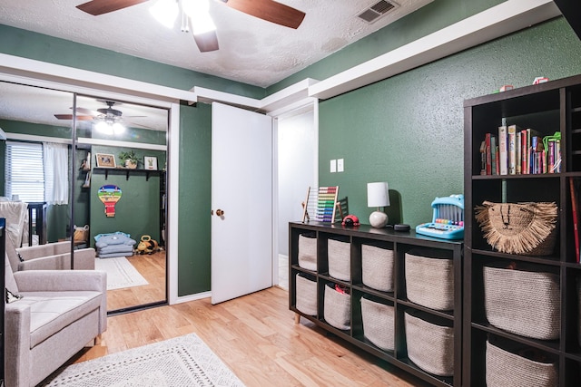 interior space featuring visible vents, a textured ceiling, a textured wall, and wood finished floors