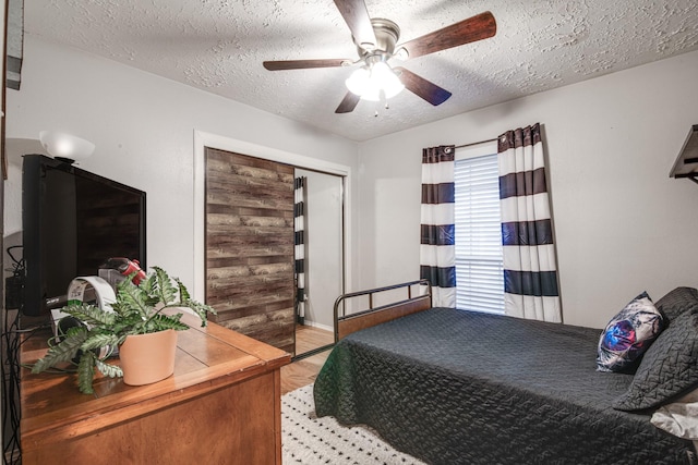 bedroom with a ceiling fan, light wood-style floors, a closet, and a textured ceiling