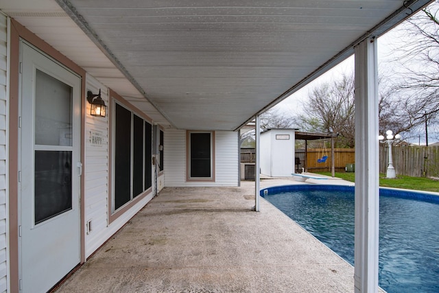 view of swimming pool with a patio, an outbuilding, a fenced in pool, a fenced backyard, and a diving board