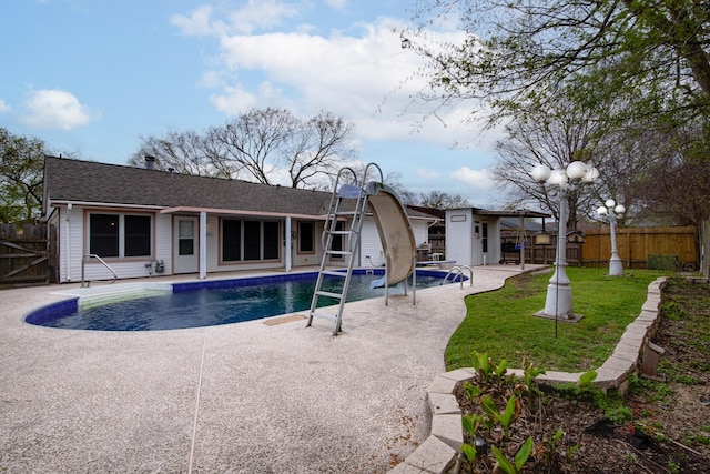 view of swimming pool featuring a patio, a fenced in pool, a yard, a fenced backyard, and an outdoor structure