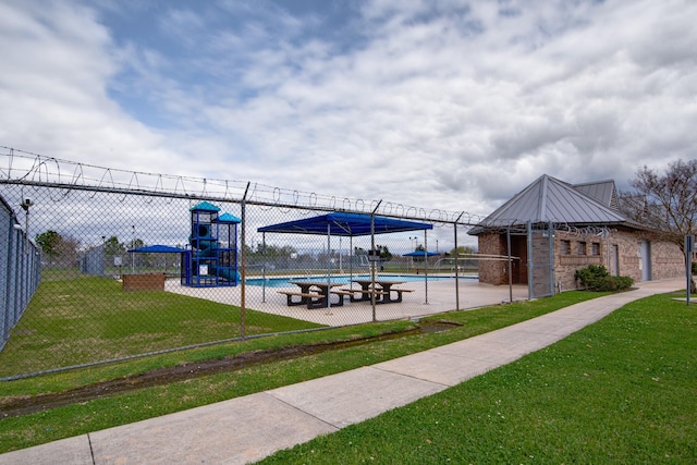 view of property's community with playground community, a lawn, and fence