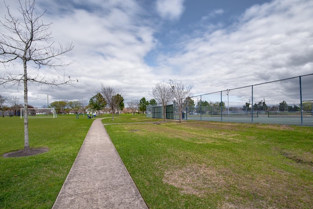 view of community featuring a tennis court and fence