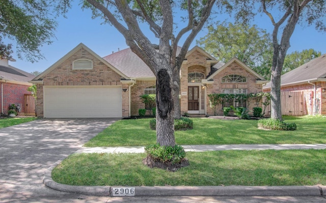 traditional-style house with a garage, a front yard, concrete driveway, and brick siding