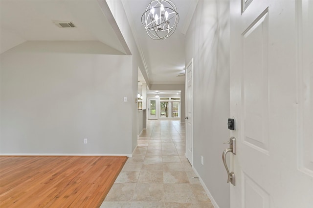 corridor with baseboards, visible vents, vaulted ceiling, crown molding, and a notable chandelier