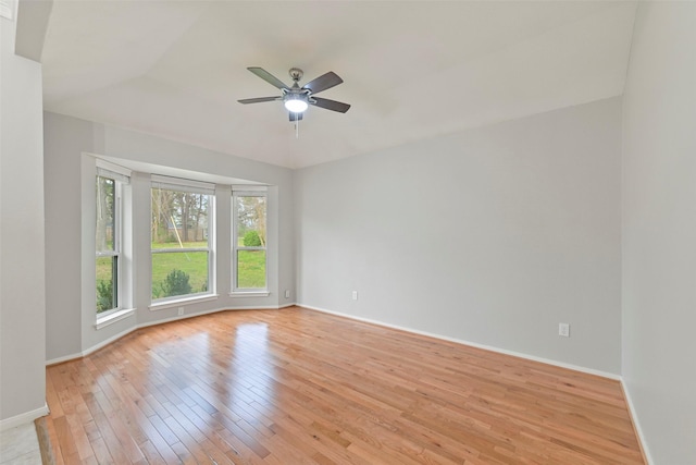 spare room with ceiling fan, light wood-style flooring, and baseboards